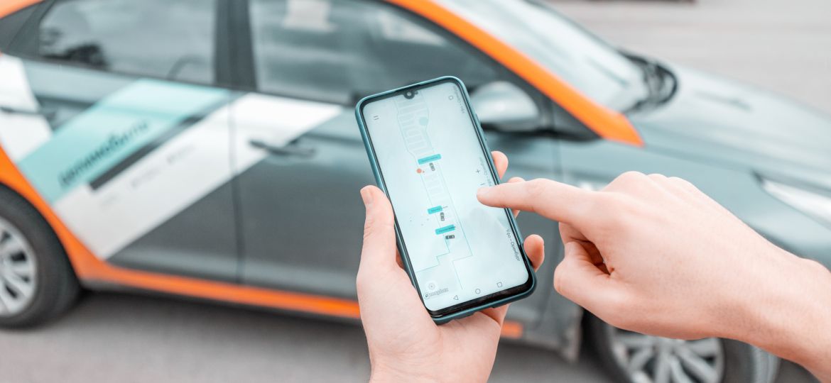 11 May 2020, Ufa, Russia: young person on a smartphone books a car in the Delimobil carsharing app to get around the city. New generation chooses not to own a car but to rent a vehicle